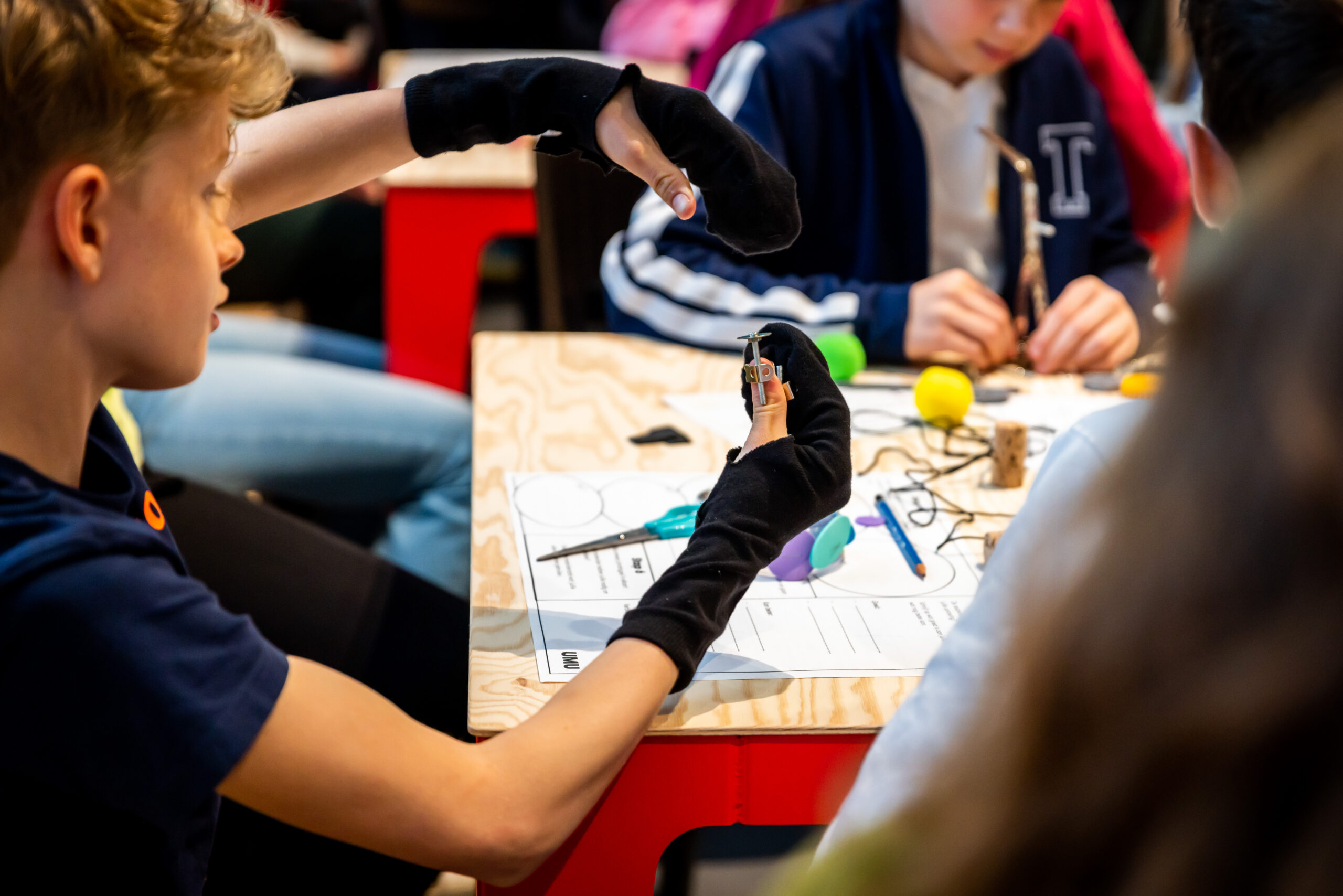Een jongen heeft zwarte handschoenen aan en is aan het knutselen